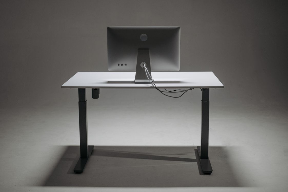 Vista traseira de mesa de escritório com monitor e cabos conduzidos junto à estrutura