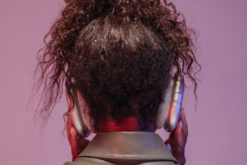 The Back View of a Woman Listening to Music with Wireless Headphones