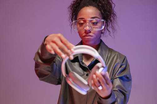 A Woman with a Goggles Holding a Headphone