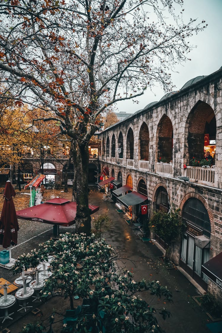 Old Arched Passage Of Building And Inner Yard With Cafe