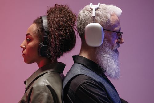 Free Creative studio shot of a black woman and a white man with headphones, showcasing diversity and technology. Stock Photo