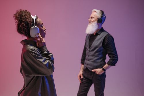 Free A black woman and a bearded senior man enjoy music with headphones in a modern studio setting. Stock Photo