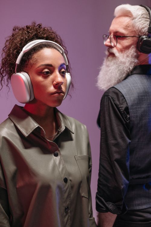 Free Portrait of an African American woman and senior man wearing headphones in a modern setting. Stock Photo