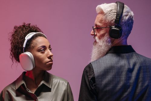 Free An African American woman and a Caucasian man wearing headphones, enjoying music together indoors. Stock Photo