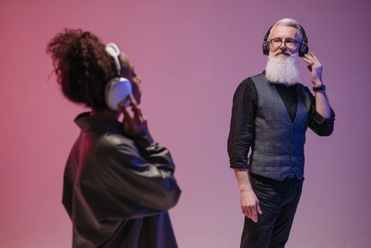 Elderly man and woman with headphones enjoying music in modern studio.