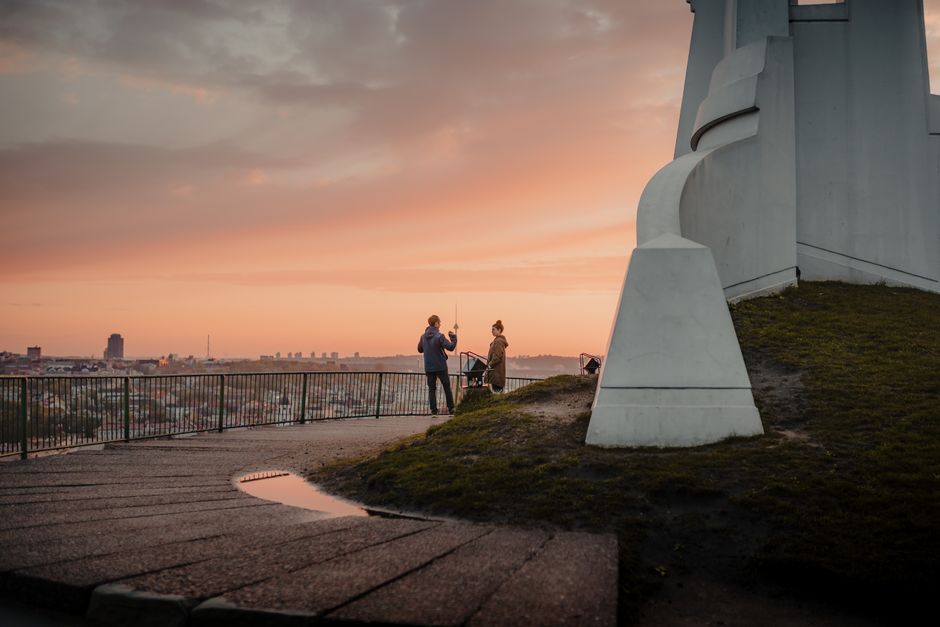 A couple shares a moment at the Three Crosses Monument overlooking Vilnius at sunset.