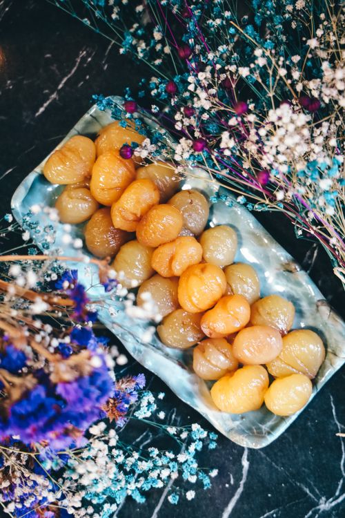 Free Top view of pickled foods on a plate surrounded by colorful dried flowers on a dark surface. Stock Photo