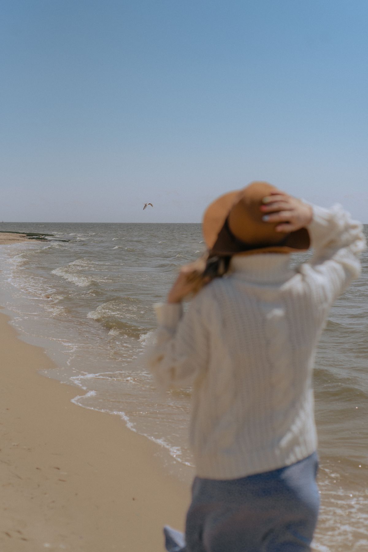 A woman in a white knit top and brown hat by the sea — the fine summer knit