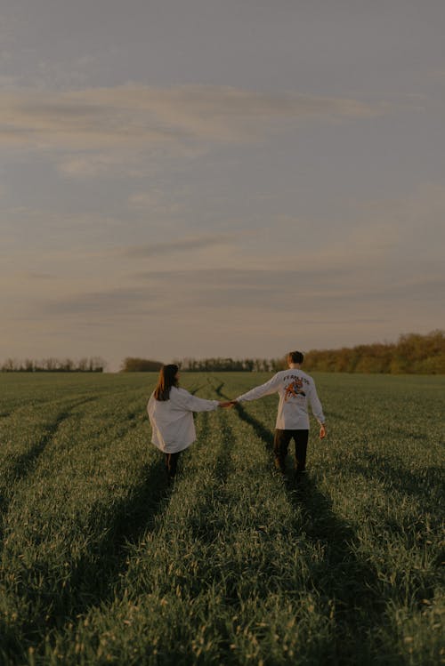 Man and Woman Holding Hands on Green Grass Field