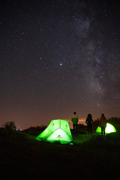 People Standing Near Tents Under Starry Night