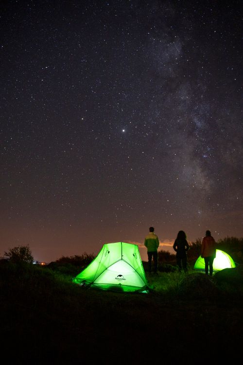 Free People camping under the starry night sky in Türkiye, surrounded by vibrant tents and the Milky Way. Stock Photo