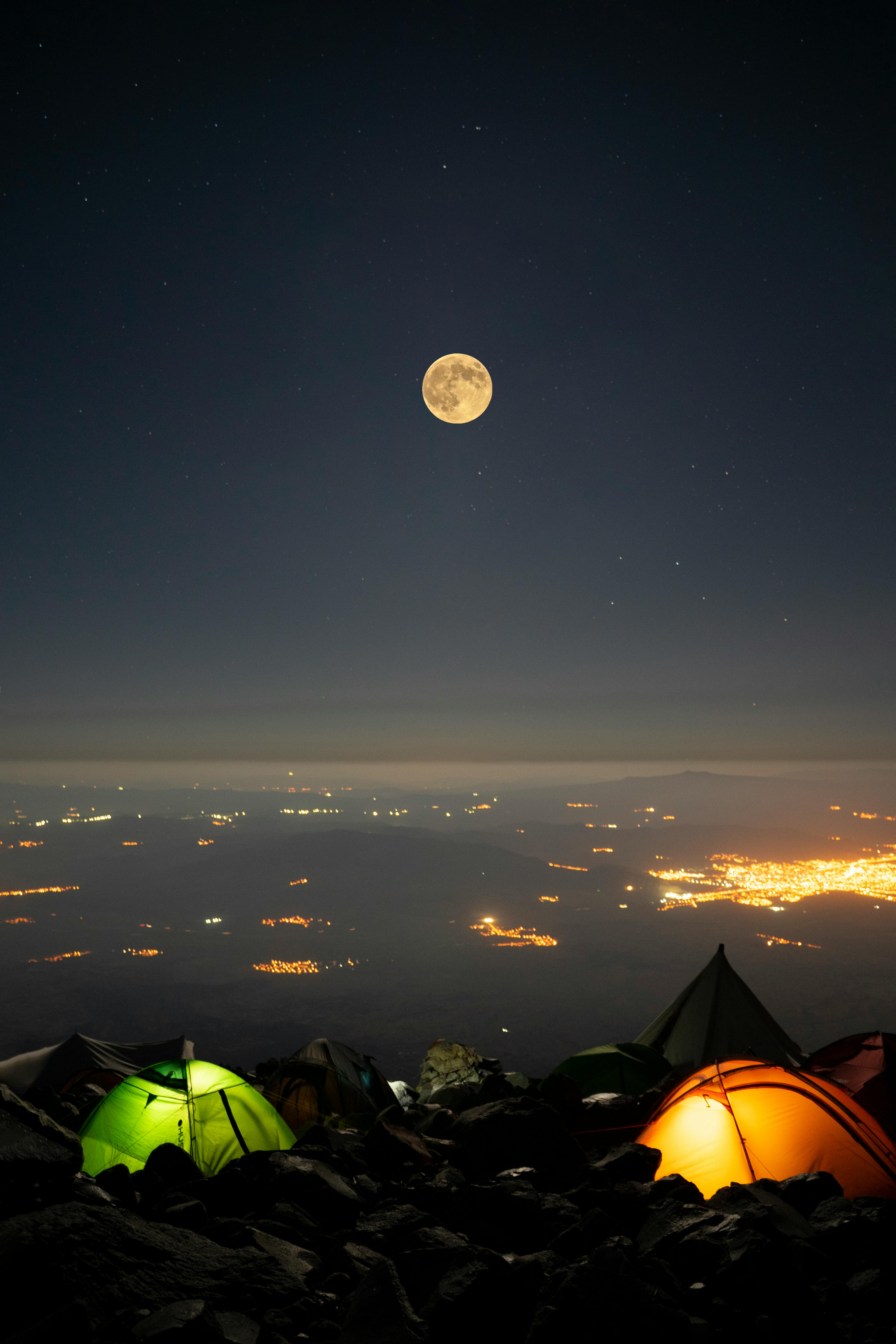 Captivating night scene with illuminated tents under a full moon in Karagüney, Turkey.