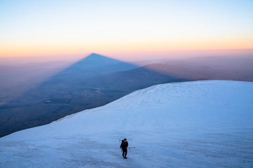 Person Climbing Mountains Covered in Snow 