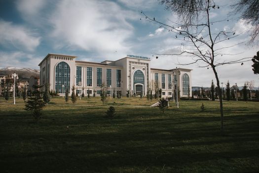 A modern building with arched windows and glass panels under a cloudy sky in Malatya, Türkiye.
