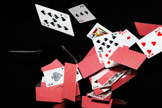 Vibrant playing cards mid-air against a stark black backdrop, showcasing movement.