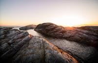 金色的晨光洒在宁静的岩石海岸上