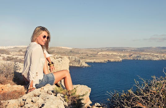 一名女子在马耳他姆加尔的悬崖上，沐浴着明媚的阳光，欣赏着壮丽的海景