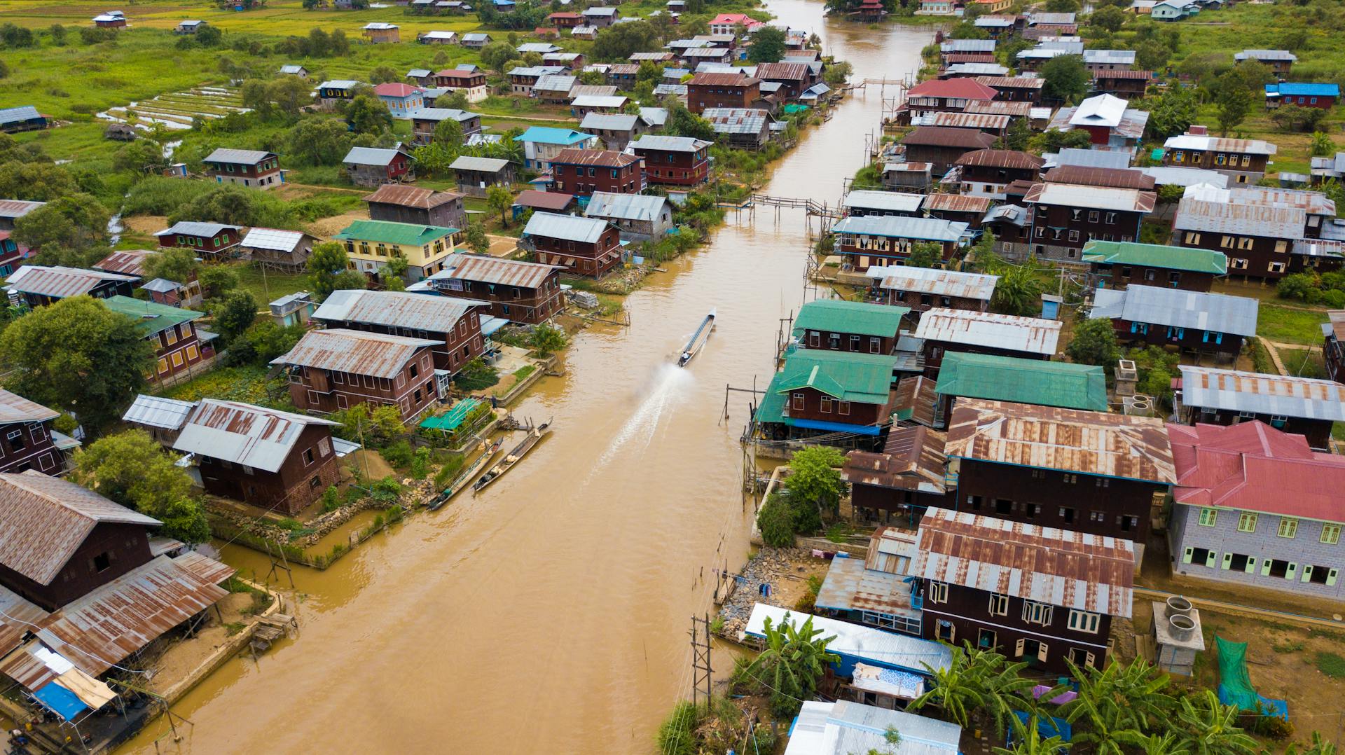 Aerial photograph showcasing the vibrant river town of Shan in Myanmar, with traditional houses lining the waterway.