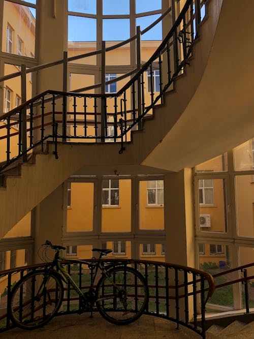 Free Bicycle Parked Along Metal Railings Under a Staircase Stock Photo