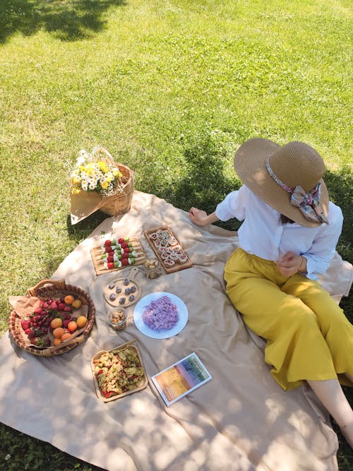 Woman Wearing a Hat Sitting on a Picnic Mat 