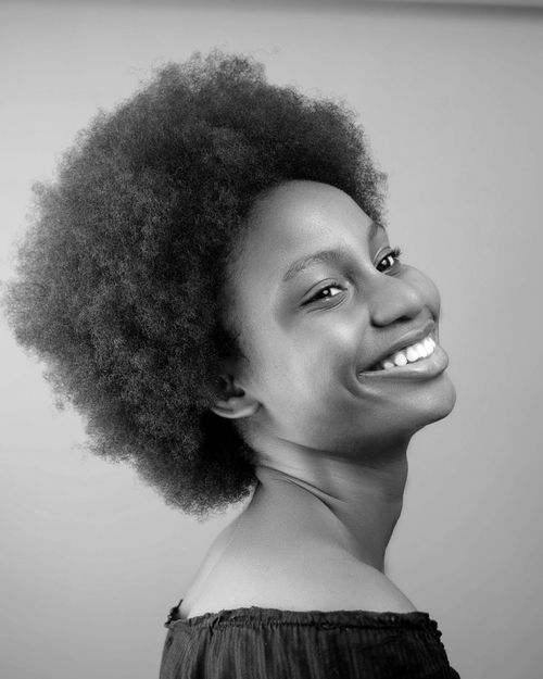 Free Black and white portrait of a smiling woman with an afro hairstyle, expressing joy and elegance. Stock Photo