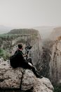 Man sitting on edge of cliff with camera