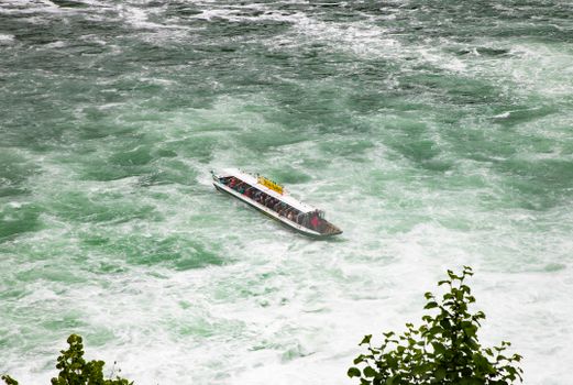 A tour boat navigates the turbulent waters of Rhine Falls in Switzerland.