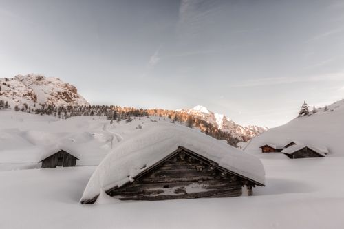Free Tranquil cabins nestled among snow-covered alpine slopes during a peaceful winter dawn. Stock Photo