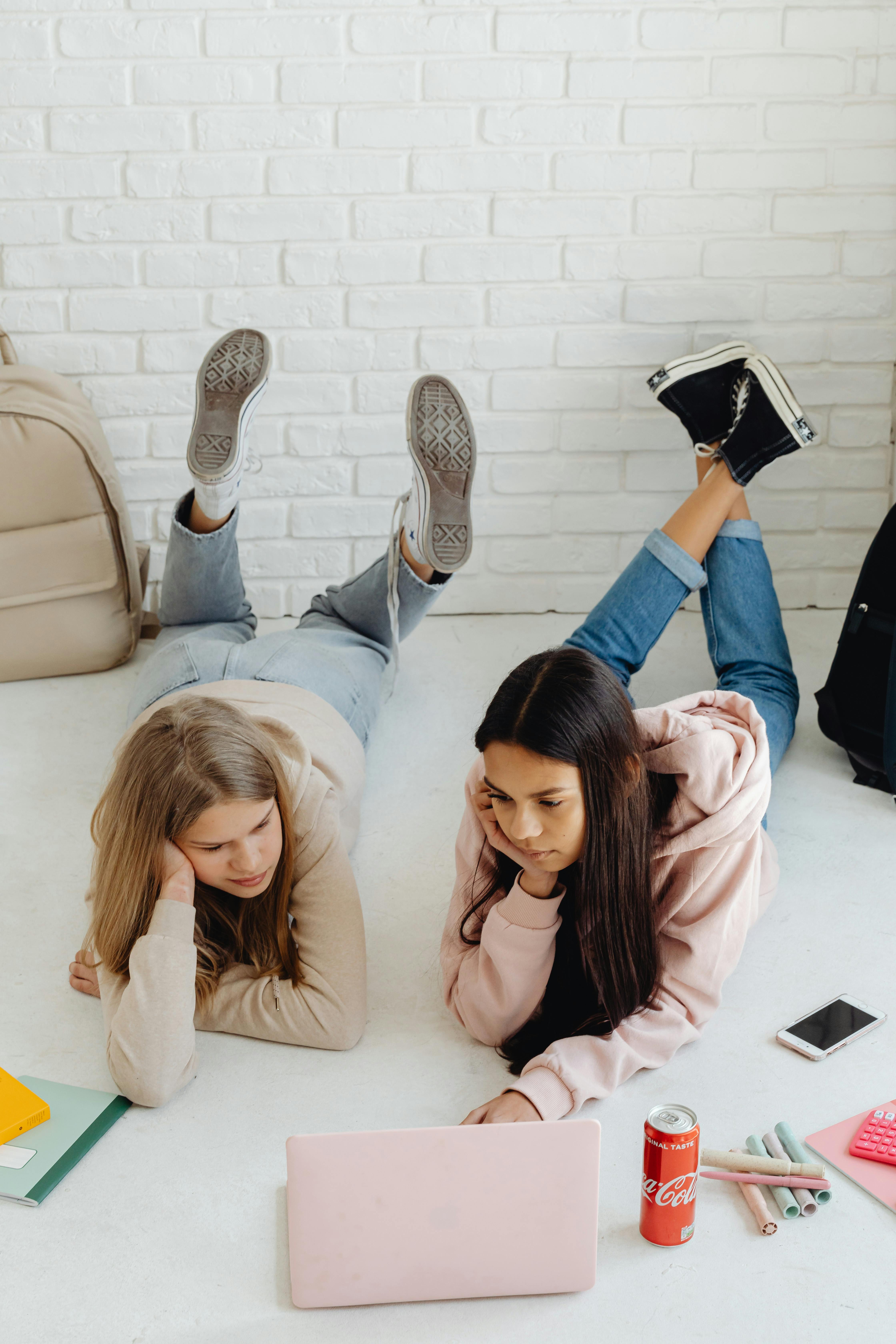 women lying down while using a laptop