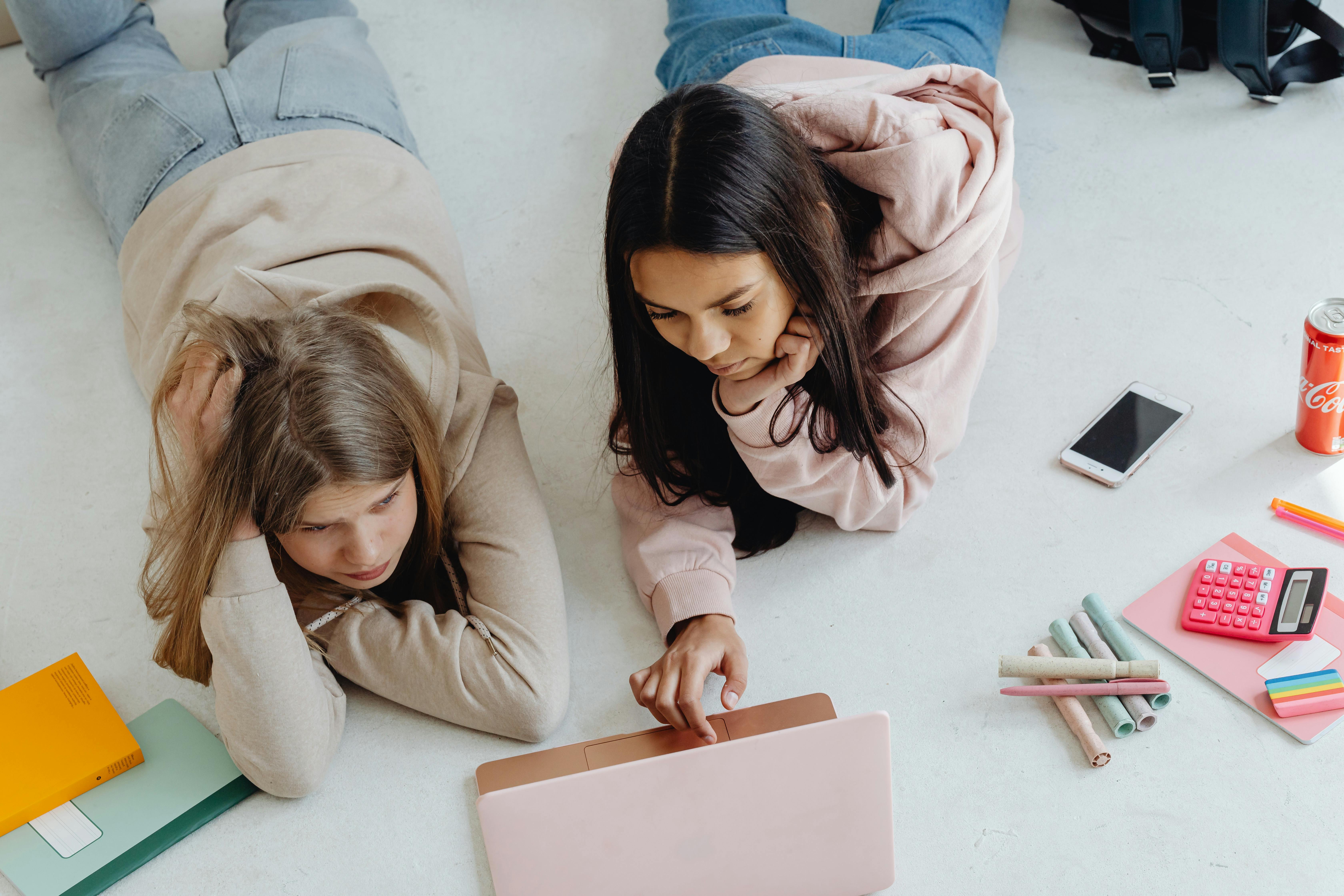 women lying down while using a laptop