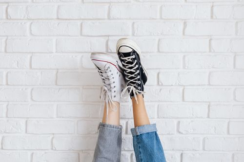 Free Casual sneakers pair showcased against a stylish white brick wall background. Stock Photo