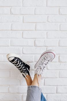 A pair of black and white sneakers against a modern white brick wall.