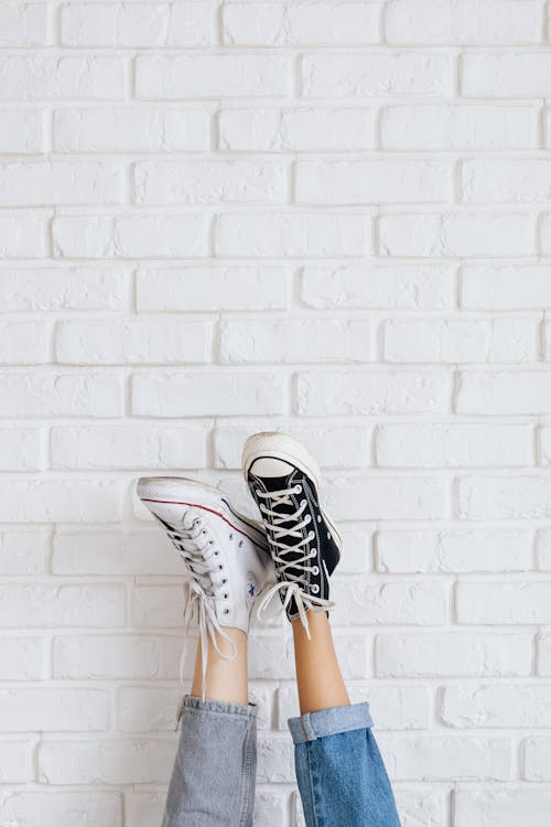 Free Photo of a Person with Black and White Sneakers Near a White Wall Stock Photo