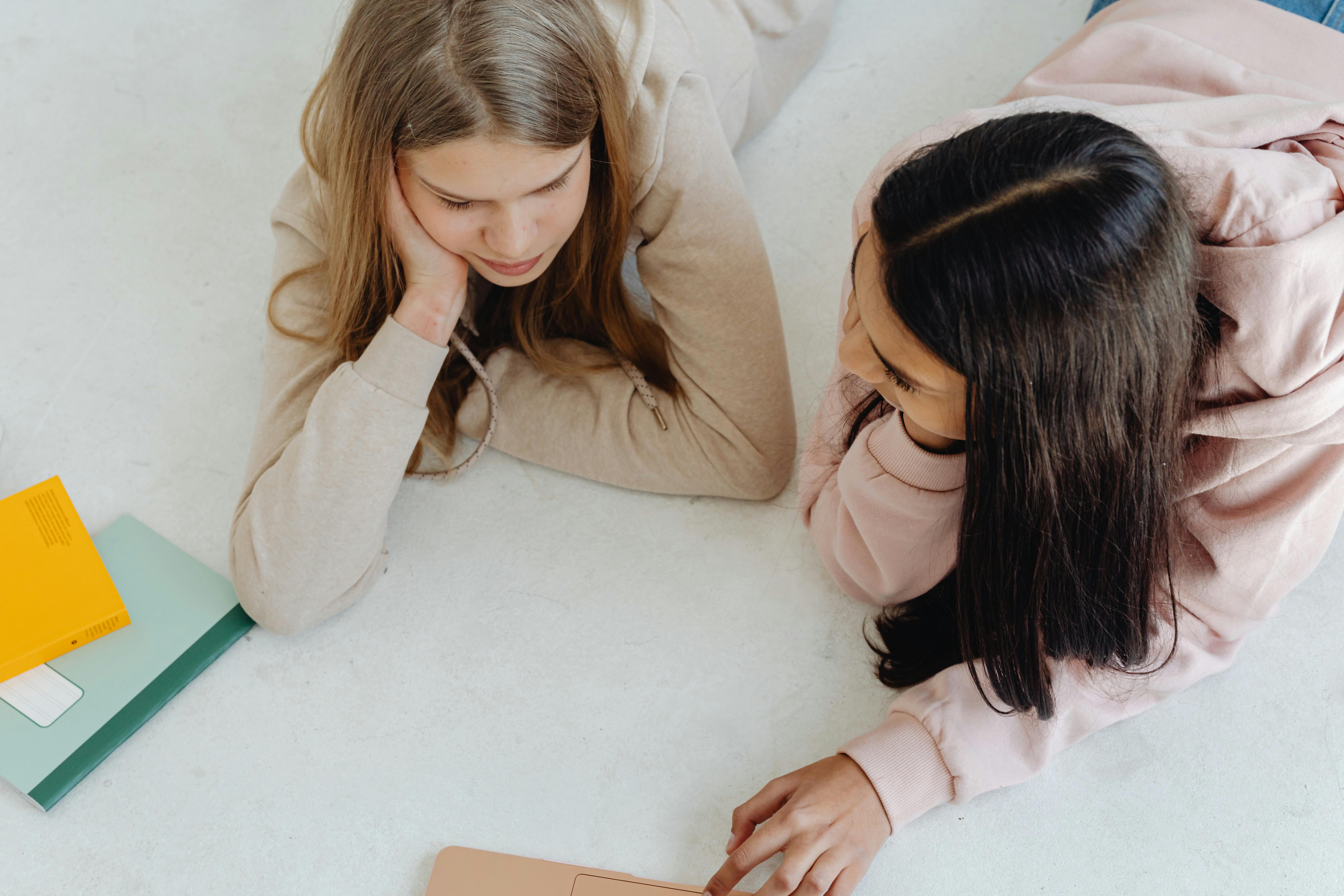 two girls having a conversation while lying down on the bed