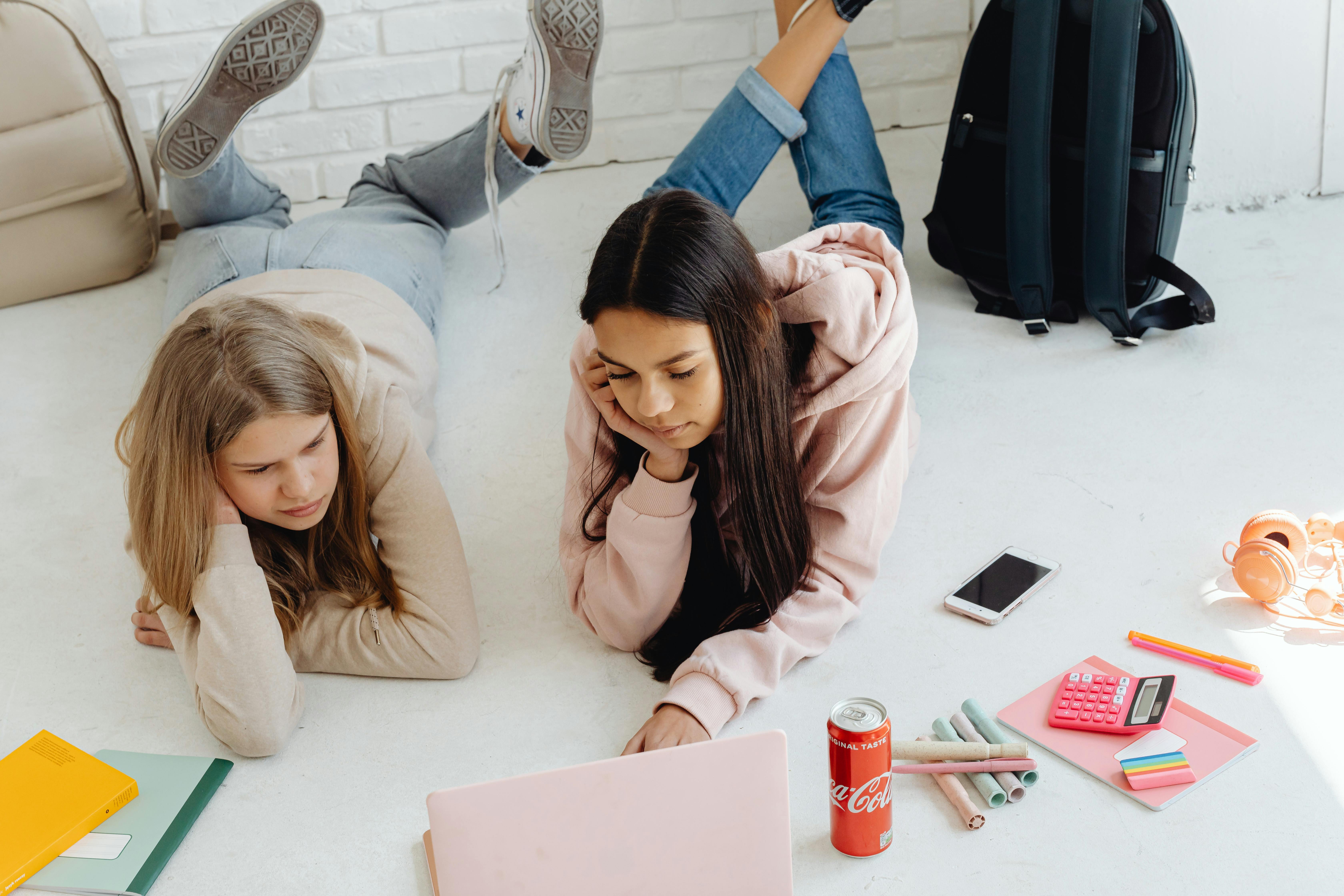 girls lying on the floor using a laptop