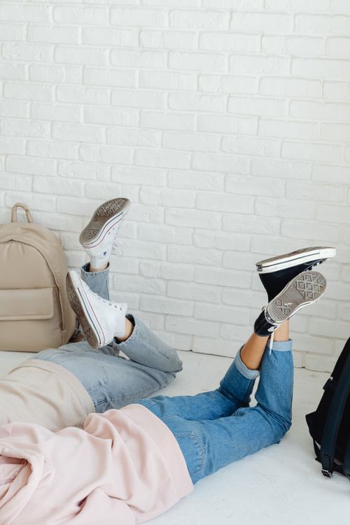 Free Two people relaxing indoors with denim pants and converse sneakers, highlighting casual style. Stock Photo