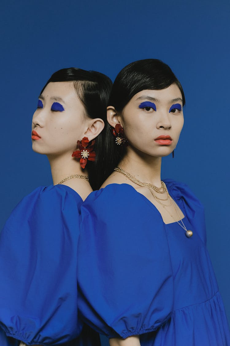 Two Women Wearing Identical Clothing And Accessories
