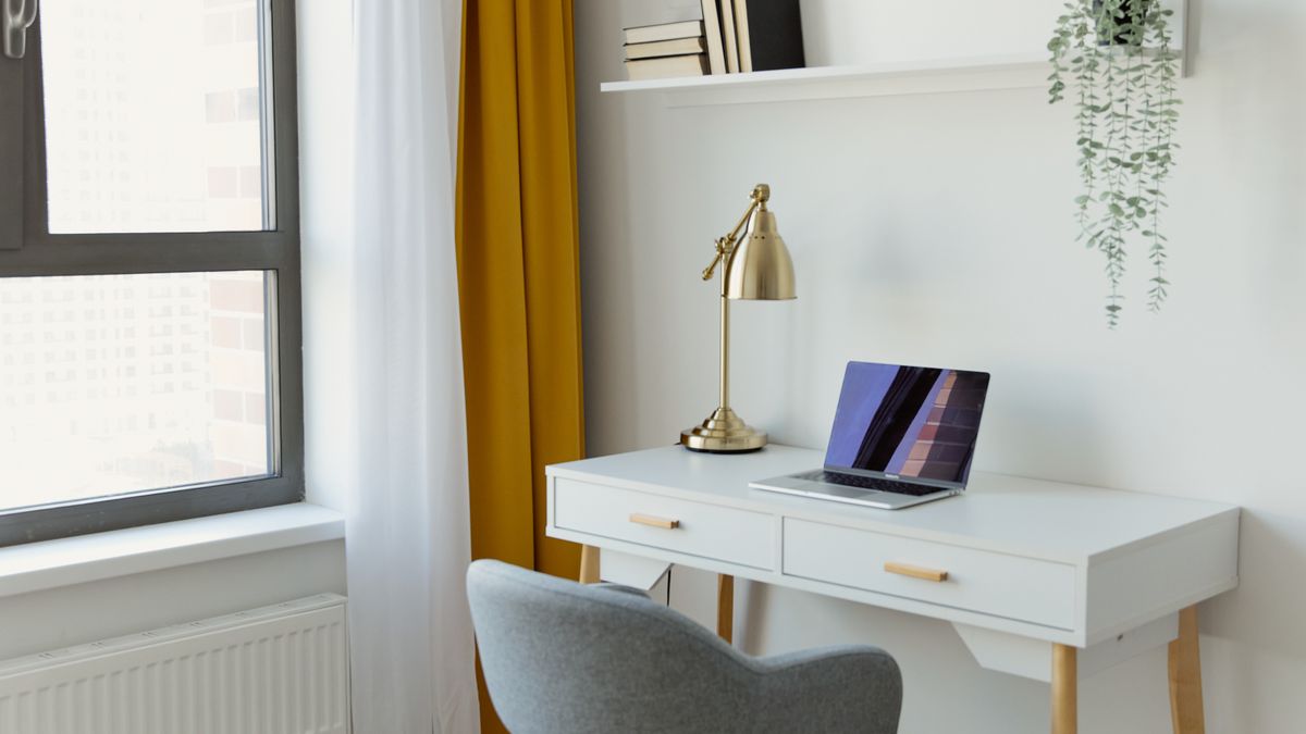 Notebook sobre mesa branca ao lado de janela em ambiente de home office organizado