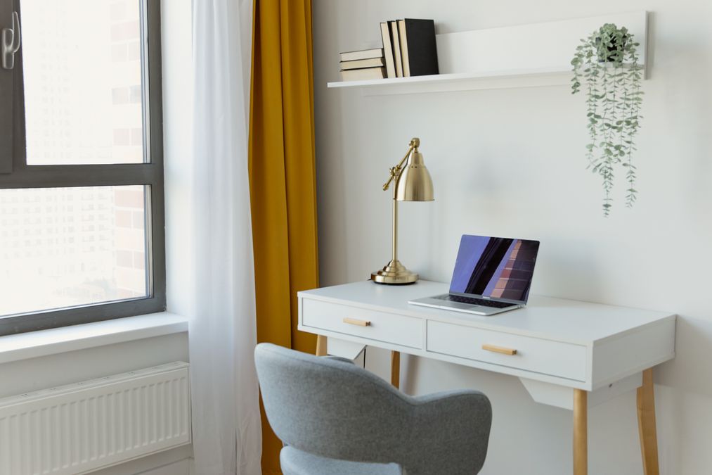 Notebook sobre mesa branca ao lado de janela em ambiente de home office organizado