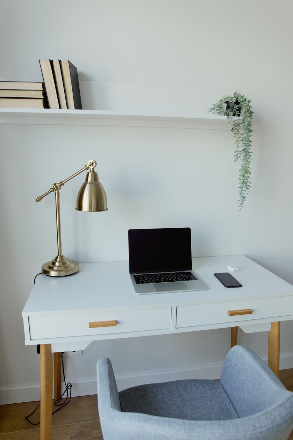 Airy home workspace with a laptop, brass lamp, and trailing plant