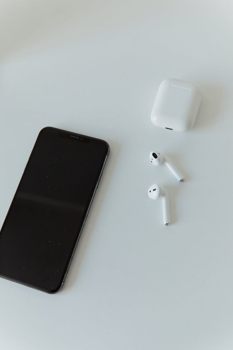 A Black Iphone And Airpods On White Table