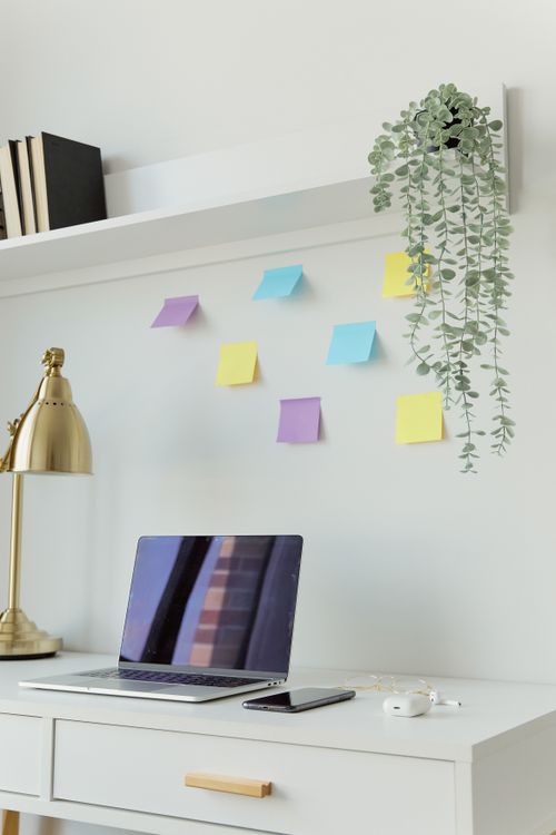 Free A minimalist home office desk with a laptop, smartphone, and sticky notes under soft natural light. Stock Photo