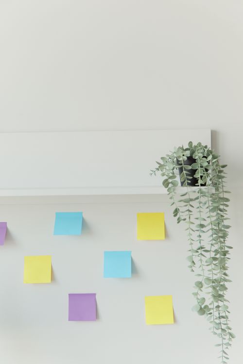 A minimalist home office desk with a laptop, smartphone, and sticky notes used for tracking client follow-ups