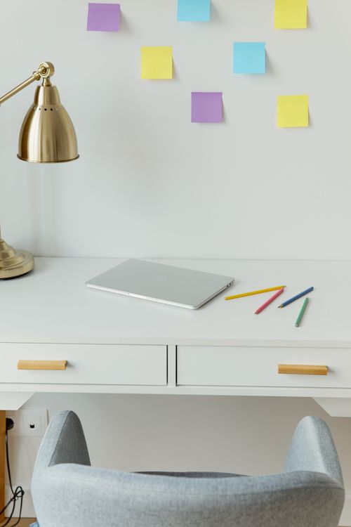 Free Minimalist workspace featuring laptop, sticky notes, and colorful pens on a white desk. Stock Photo