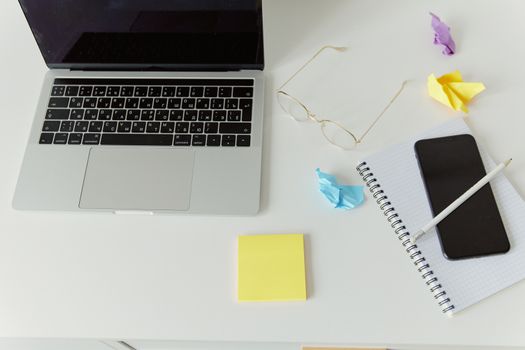A minimalistic office desk with a laptop, notepad, and crumpled paper for productivity.