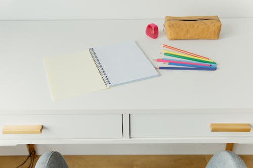 Free White Notebook Besides Colored Pencils on White Table Stock Photo