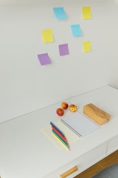 A clean workspace featuring stationery, apples, and sticky notes for productivity.