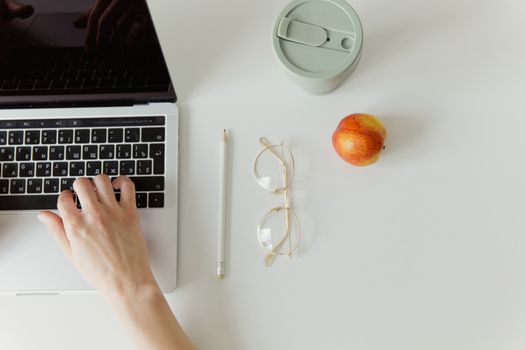 Simple minimalist workspace with a laptop, coffee cup, and apple. Ideal for office theme.
