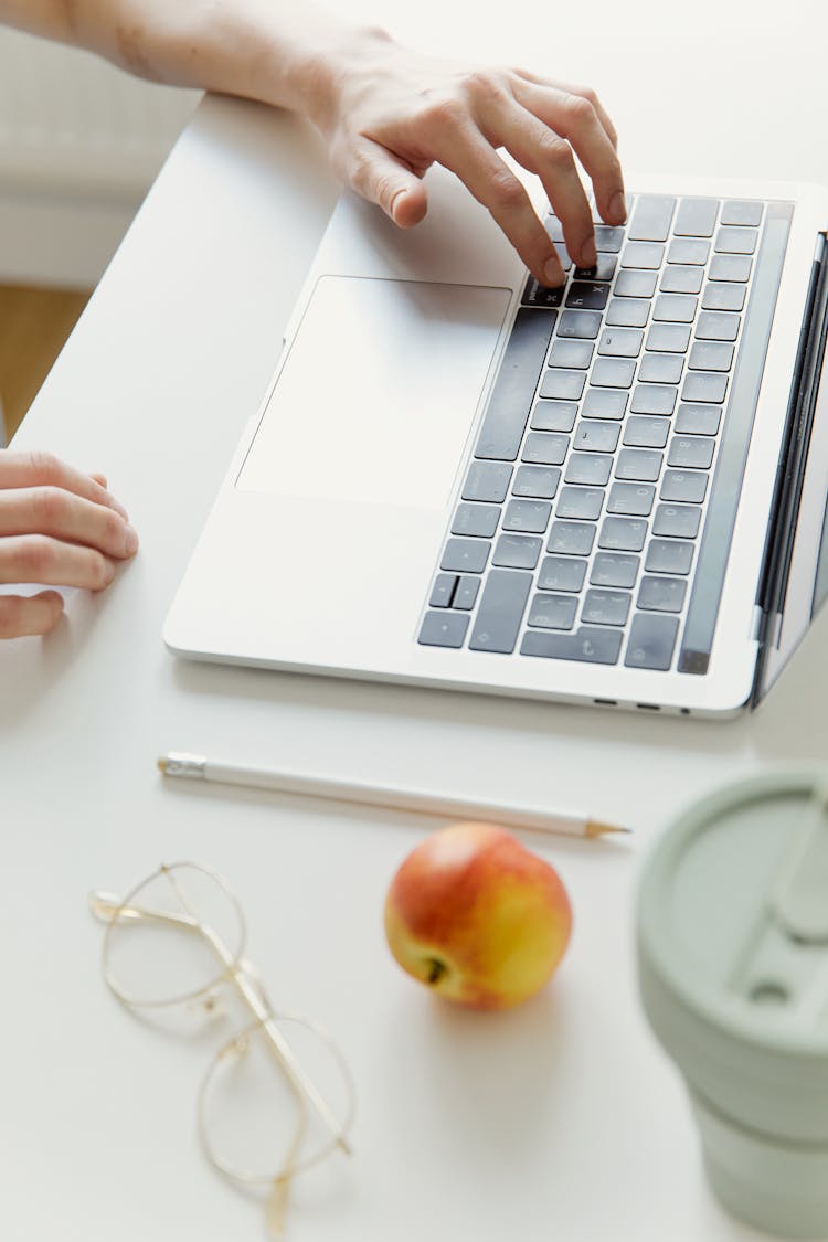 A Person Typing On The Keyboard Of A Laptop