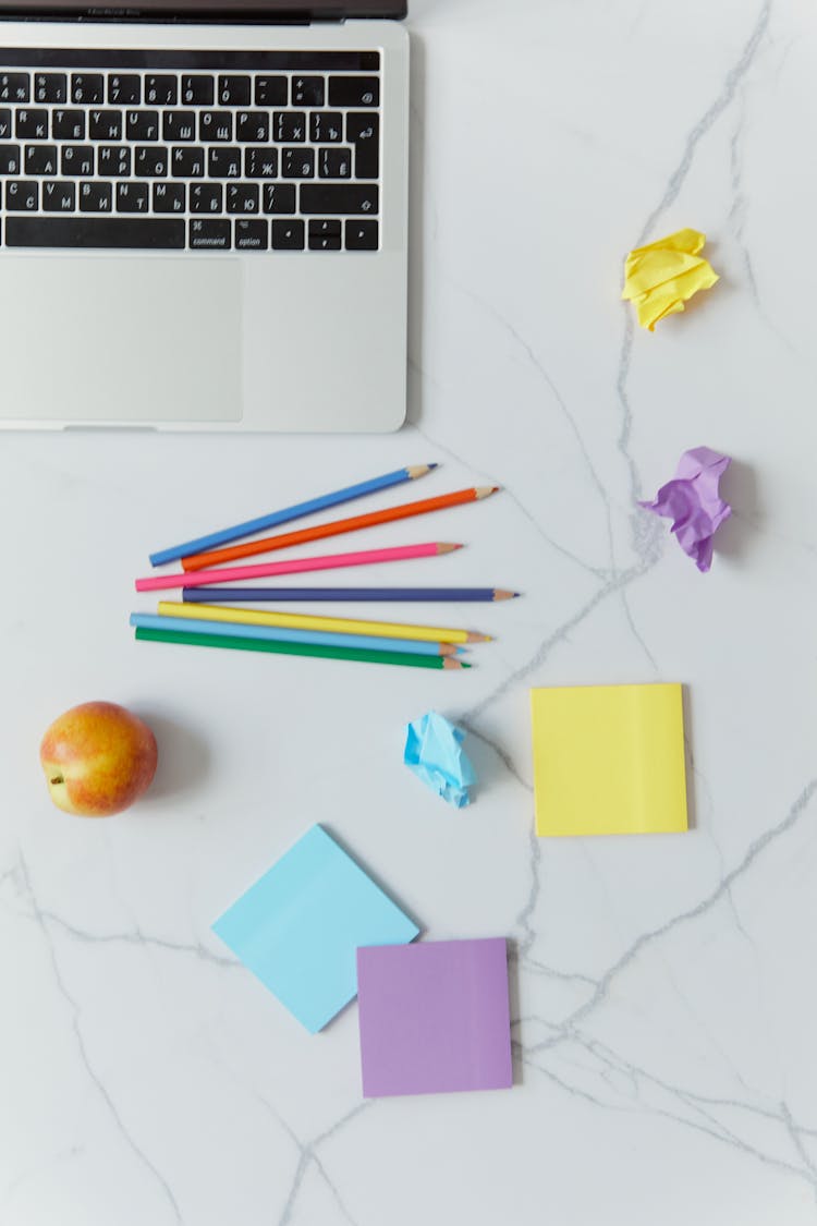 Colorful Stationeries Beside Laptop On A White Surface